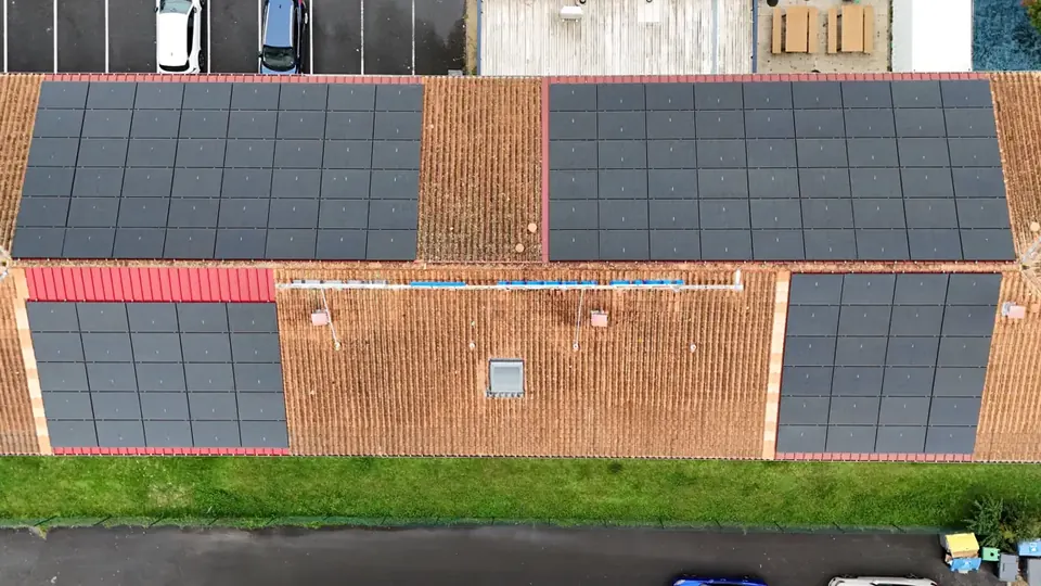 Quatre champs de panneaux photovoltaïques sur la toiture tuile d'un hôtel à Bordeaux, vue de drone