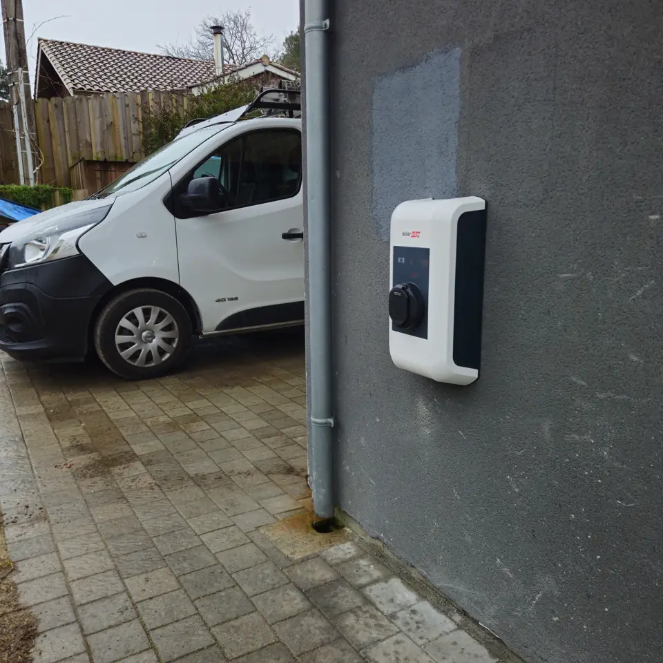 Borne de recharge véhicule électrique SolarEdge au mur, à côté de l'utilitaire